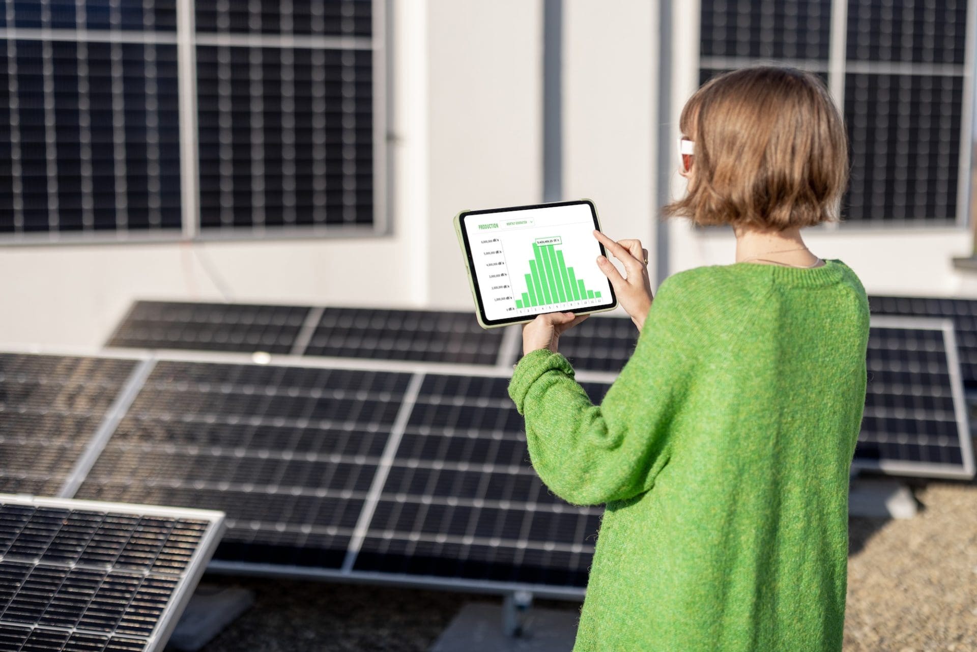 Woman monitors energy production from the solar power plant with a digital tablet