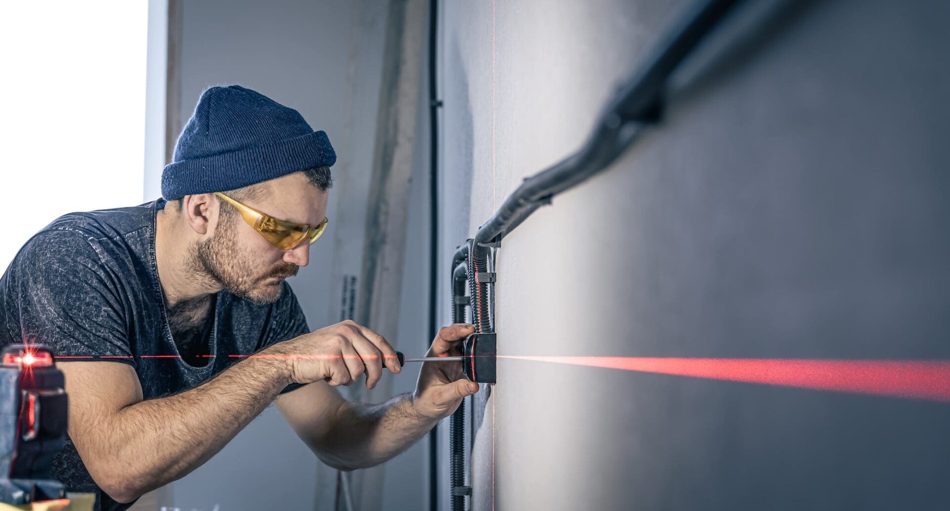 An electrician is mounting electric sockets on the white wall indoors.