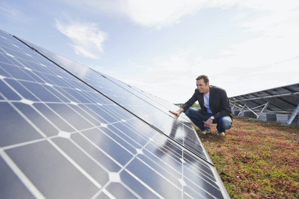 Germany, Munich, Man touching solar panel in solar plant